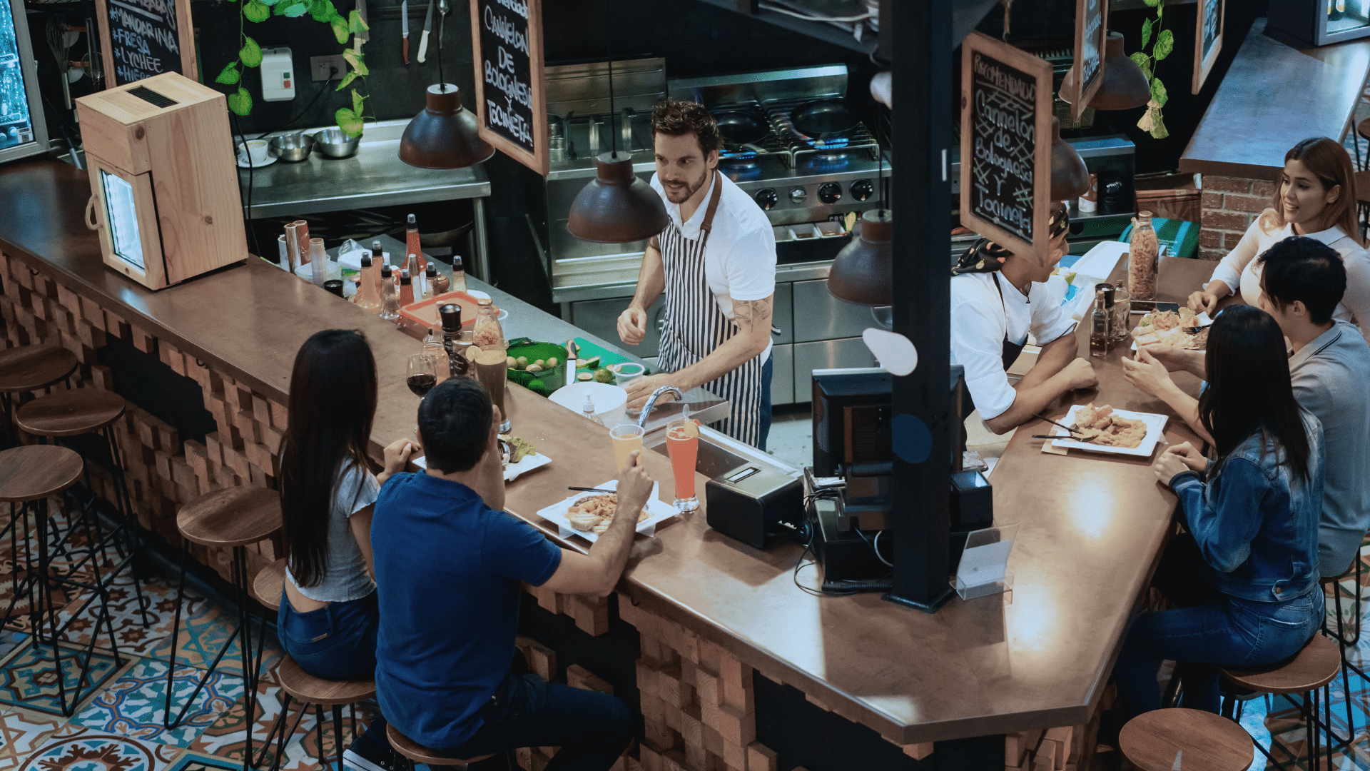 Restaurant staff assisting customers at the counter with the Zoku Point of Sale system in a busy restaurant setting.